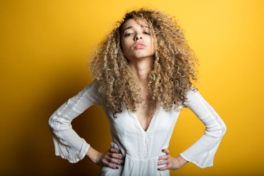 Woman in a white bell-sleeve wrap blouse against a yellow backdrop