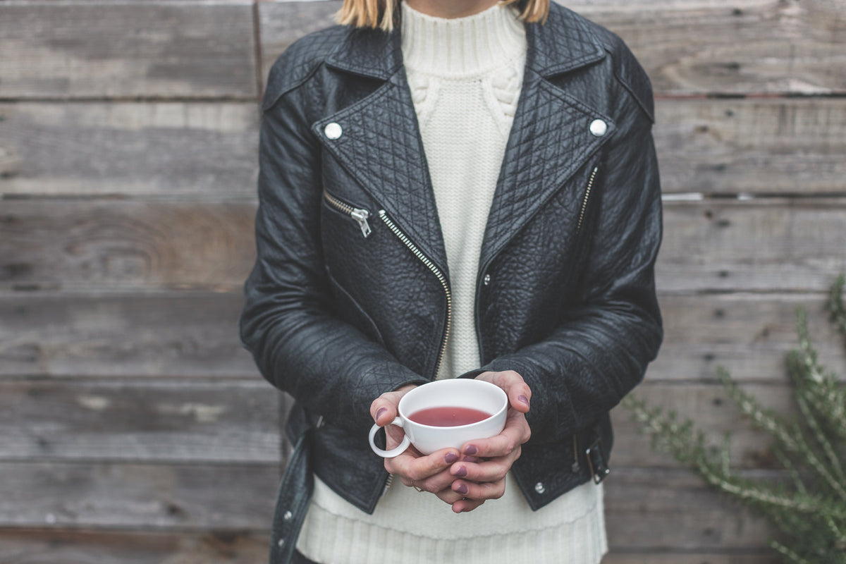 Woman in a black quilted leather jacket holding a cup of tea