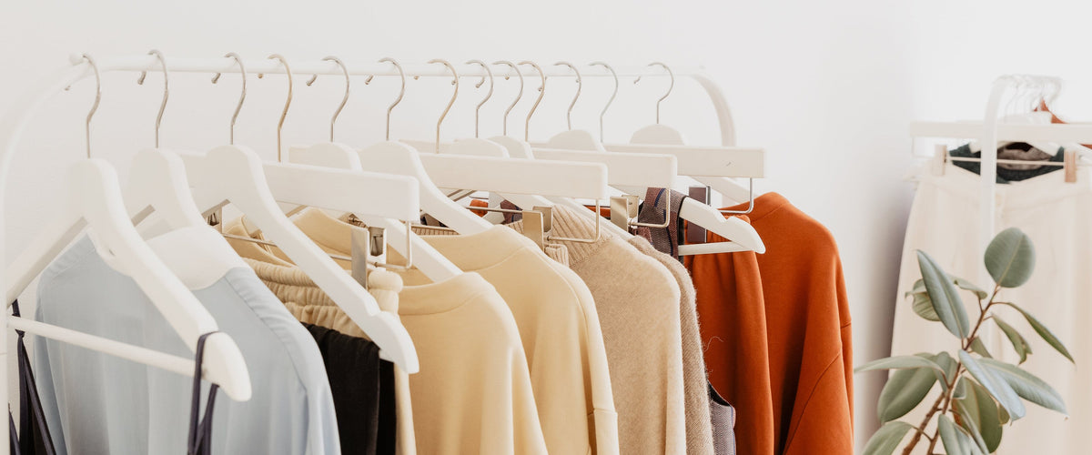 Neutral-toned clothing on white hangers on a minimalist rack