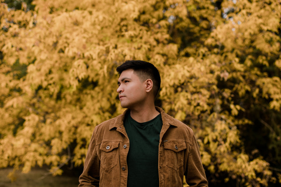 Man in a cognac brown trucker jacket in front of autumn leaves