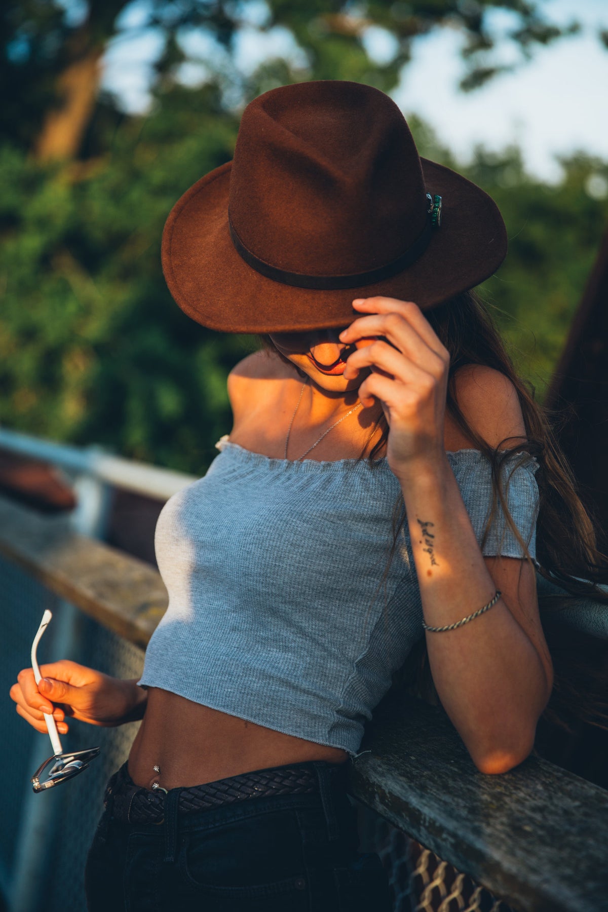 Woman in a grey off-shoulder crop top and a brown hat